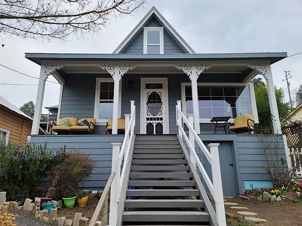 Blue cottage with white-trimmed porch and horizontal siding