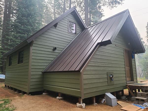 Green cabin with horizontal siding and steep metal roof
