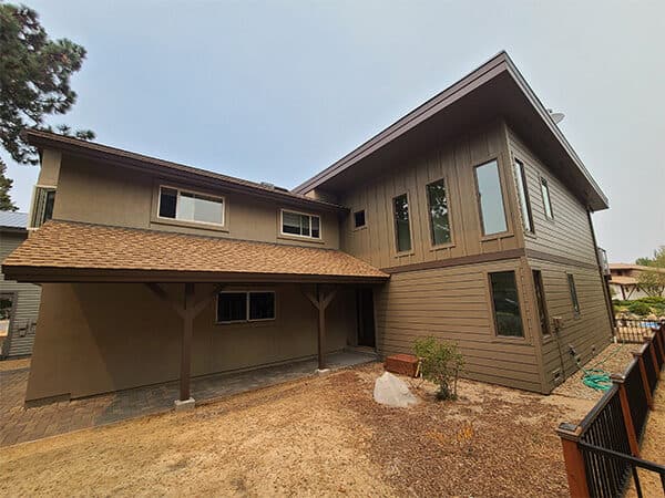 Rear of tan multi-level home with mixed siding and tall windows