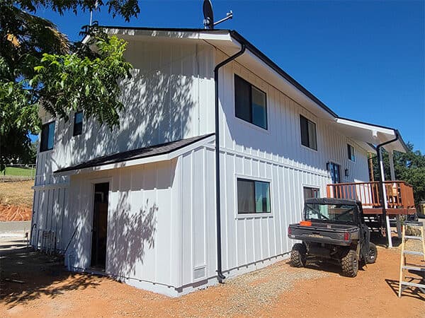 White two-story home with vertical lower siding and wood deck