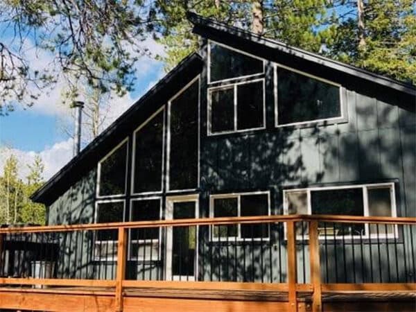 Cabin exterior before siding completion with large windows and white trim