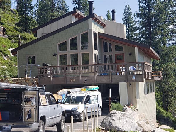 Mountain home with green vertical siding and large triangular windows