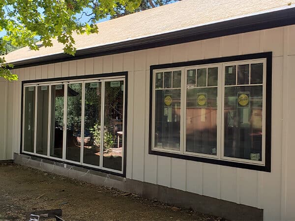 Beige vertical panel siding with dark battens and black-trimmed windows